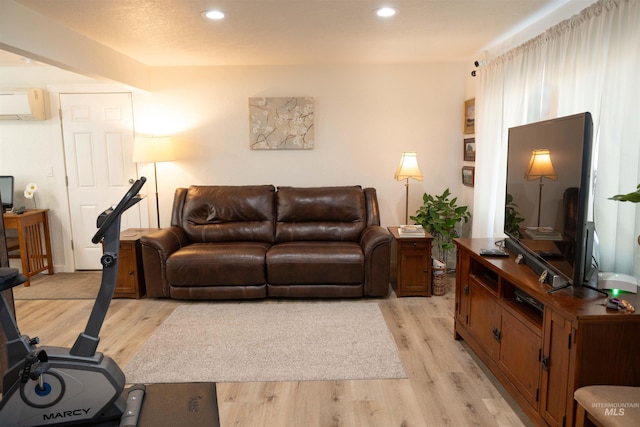 living room featuring a wall mounted air conditioner and light wood-type flooring