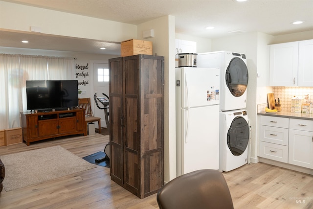 washroom with stacked washer / dryer and light hardwood / wood-style floors