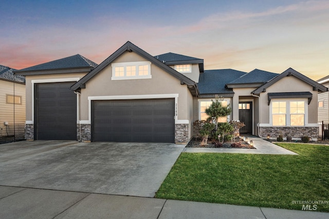 view of front of home with stucco siding, a front yard, a garage, stone siding, and driveway