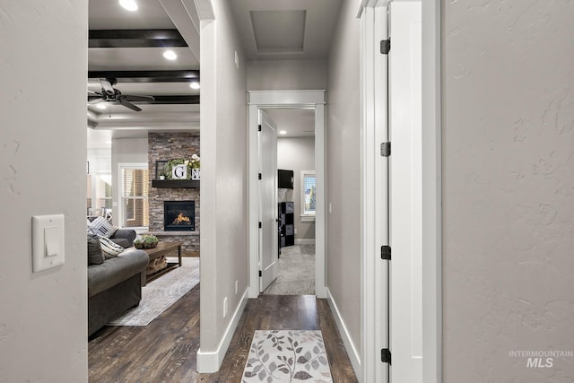 hallway featuring dark wood-style floors, beam ceiling, and baseboards