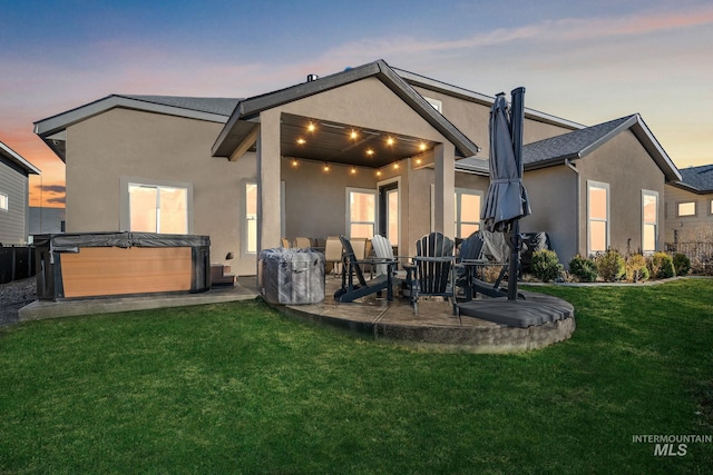 back of house with a patio area, a yard, a hot tub, and stucco siding