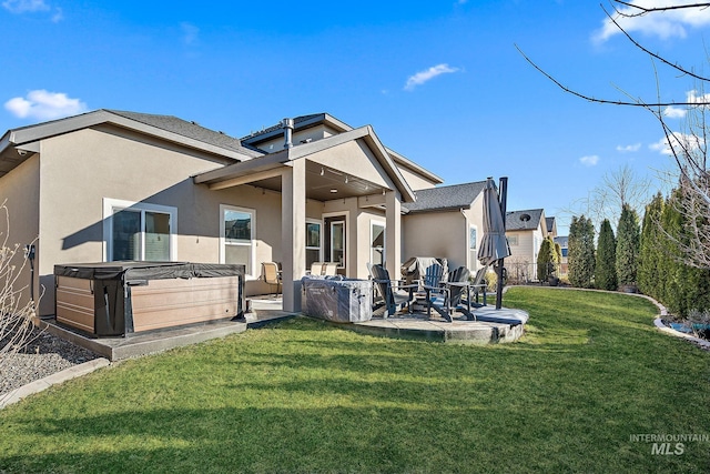 back of house featuring a yard, a hot tub, a patio, and stucco siding