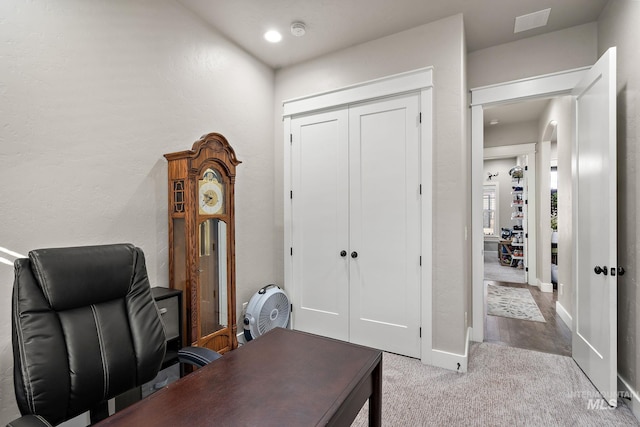 office area with carpet floors, baseboards, visible vents, and a textured wall