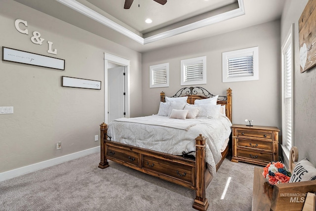 bedroom with ceiling fan, carpet flooring, baseboards, a tray ceiling, and crown molding