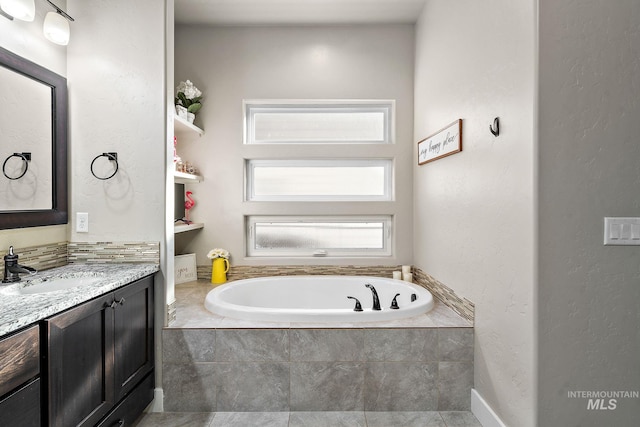 bathroom with a garden tub and vanity