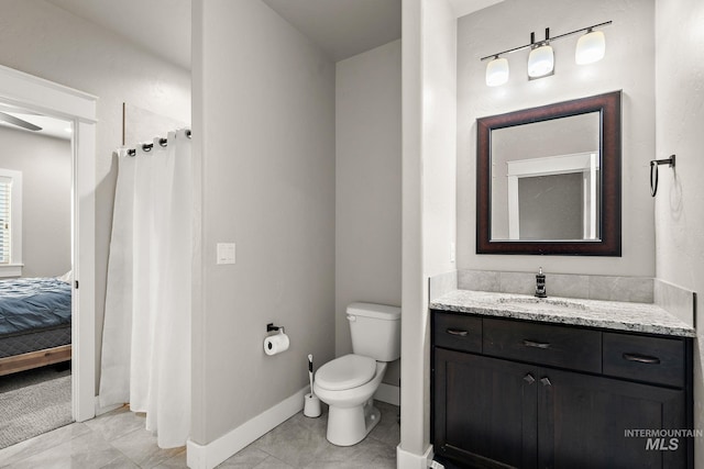 ensuite bathroom featuring a shower with shower curtain, toilet, vanity, baseboards, and tile patterned floors