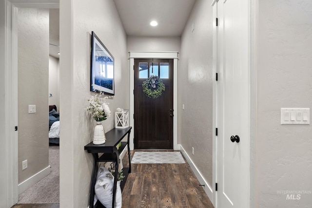 foyer entrance featuring baseboards, dark wood-style flooring, and a textured wall