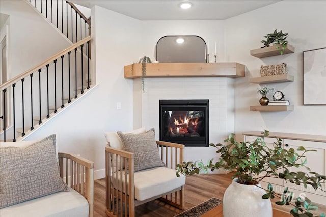 living area featuring baseboards, a glass covered fireplace, wood finished floors, stairs, and recessed lighting