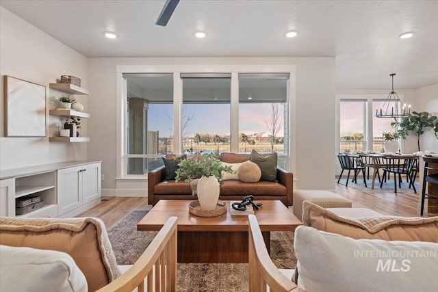 living area featuring light wood-style floors, baseboards, a chandelier, and recessed lighting