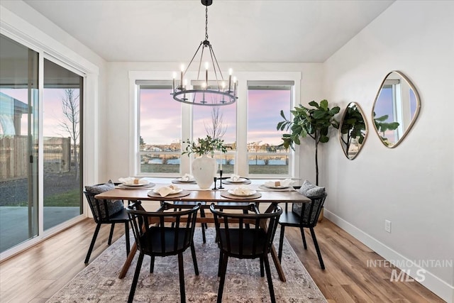 dining room featuring an inviting chandelier, light wood-style flooring, and baseboards