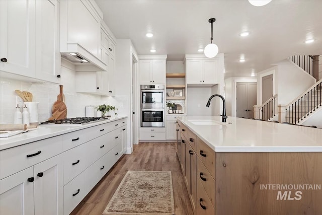 kitchen with tasteful backsplash, appliances with stainless steel finishes, light wood-type flooring, open shelves, and a sink