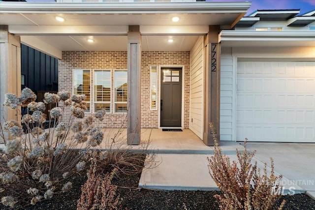 view of exterior entry featuring a garage and brick siding