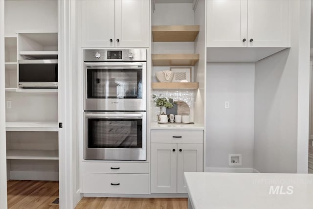 kitchen featuring light wood-style floors, double oven, open shelves, and light countertops