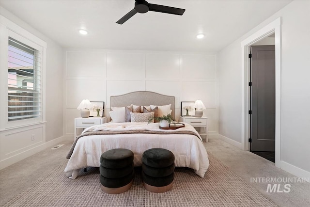 bedroom featuring a ceiling fan, carpet flooring, a decorative wall, and baseboards