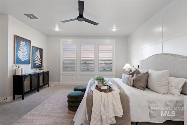 bedroom featuring visible vents, a decorative wall, a ceiling fan, carpet flooring, and baseboards