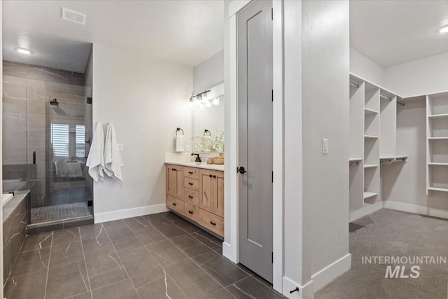 full bath with vanity, visible vents, baseboards, a spacious closet, and a shower stall