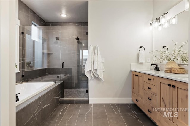 full bathroom featuring double vanity, a sink, a shower stall, baseboards, and a bath