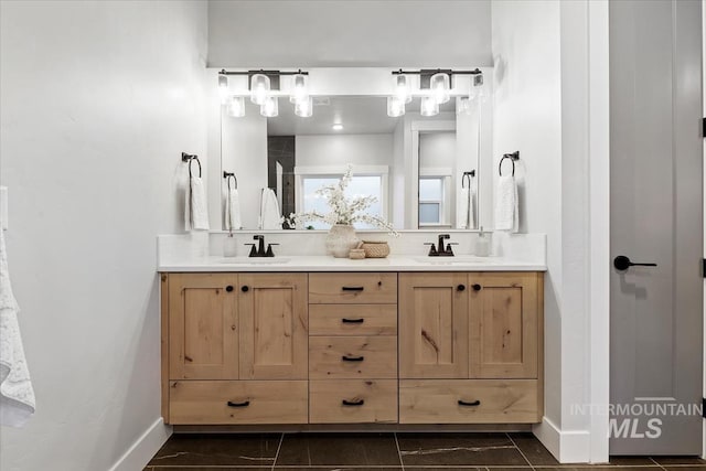 full bathroom with double vanity, a sink, and baseboards