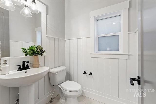 bathroom featuring a wainscoted wall, a sink, and toilet