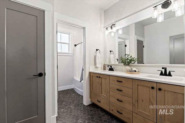 full bathroom with shower / tub combo with curtain, a sink, baseboards, and double vanity