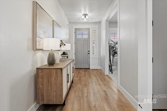 doorway featuring light wood finished floors and baseboards