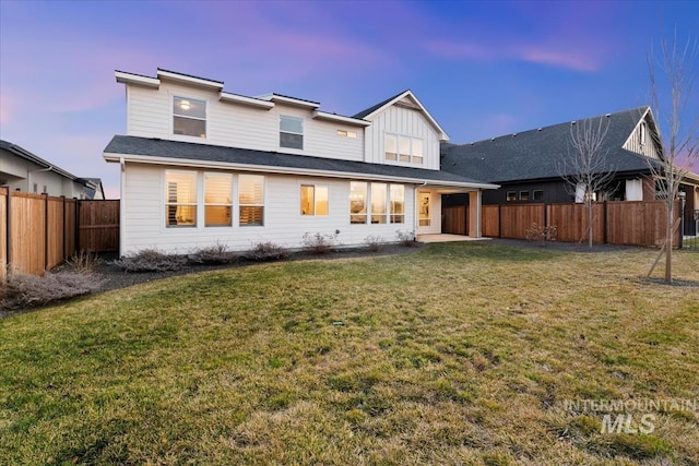 back of house featuring board and batten siding, a patio area, a fenced backyard, and a yard