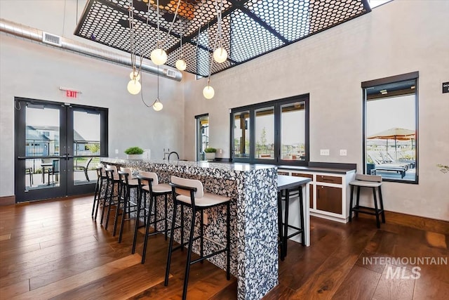 bar with dark wood-type flooring, a towering ceiling, visible vents, baseboards, and french doors