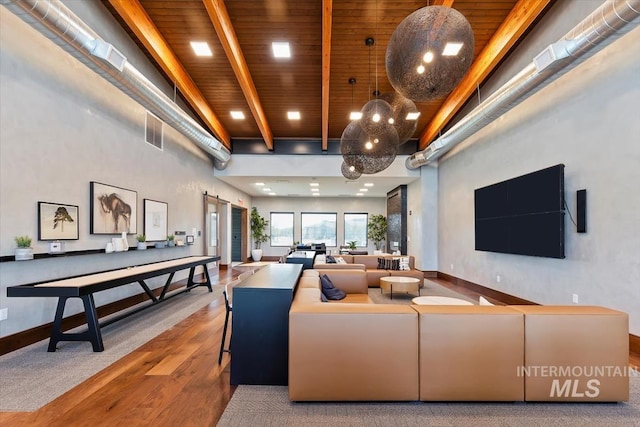 game room featuring a barn door, wooden ceiling, wood finished floors, a towering ceiling, and beam ceiling