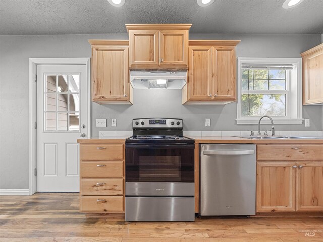 3500 W Overland, Boise, ID 83705 - kitchen featuring light wood-style flooring, range hood, appliances with stainless steel finishes, tile countertops, and light brown cabinetry