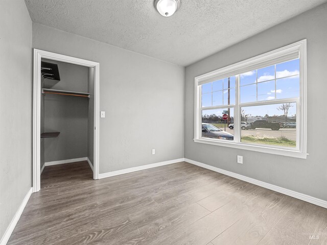 3500 W Overland, Boise, ID 83705 - unfurnished bedroom featuring a closet, wood finished floors, a spacious closet, a textured ceiling, and baseboards