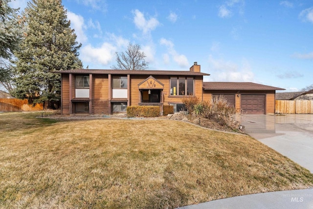 split foyer home featuring a front yard, fence, driveway, an attached garage, and a chimney