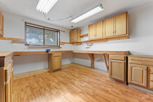 kitchen featuring light wood-style flooring, open shelves, a textured ceiling, baseboards, and built in study area