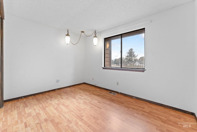 spare room with baseboards, visible vents, a textured ceiling, and light wood-style floors