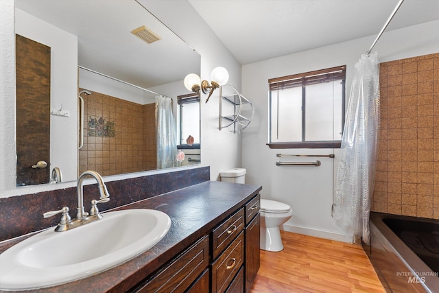 full bathroom featuring visible vents, shower / tub combo with curtain, toilet, wood finished floors, and vanity