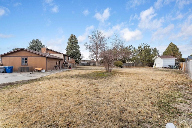 view of yard featuring a storage unit, a patio, an outdoor structure, and a fenced backyard