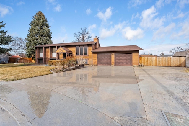 bi-level home featuring a front lawn, fence, concrete driveway, a chimney, and an attached garage