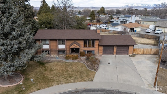 view of front facade with driveway, fence, a mountain view, a shingled roof, and a garage