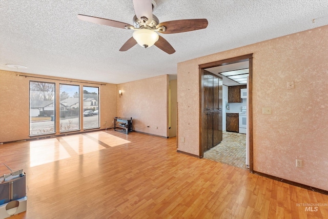 unfurnished living room with wood finished floors, baseboards, a textured wall, and a textured ceiling