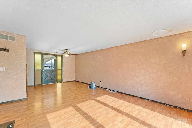 interior space featuring visible vents, a textured ceiling, wood finished floors, and a textured wall