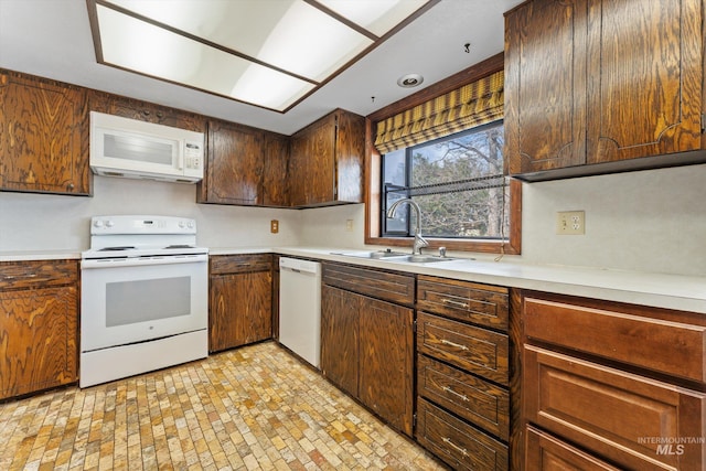 kitchen with white appliances, light countertops, and a sink