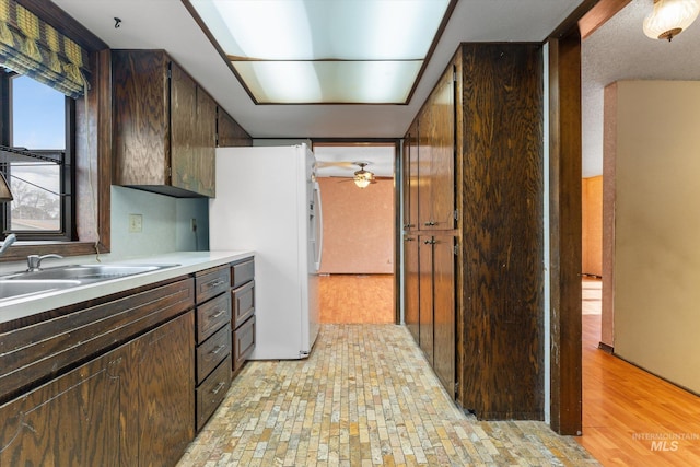 kitchen with dark brown cabinets, white refrigerator with ice dispenser, and ceiling fan