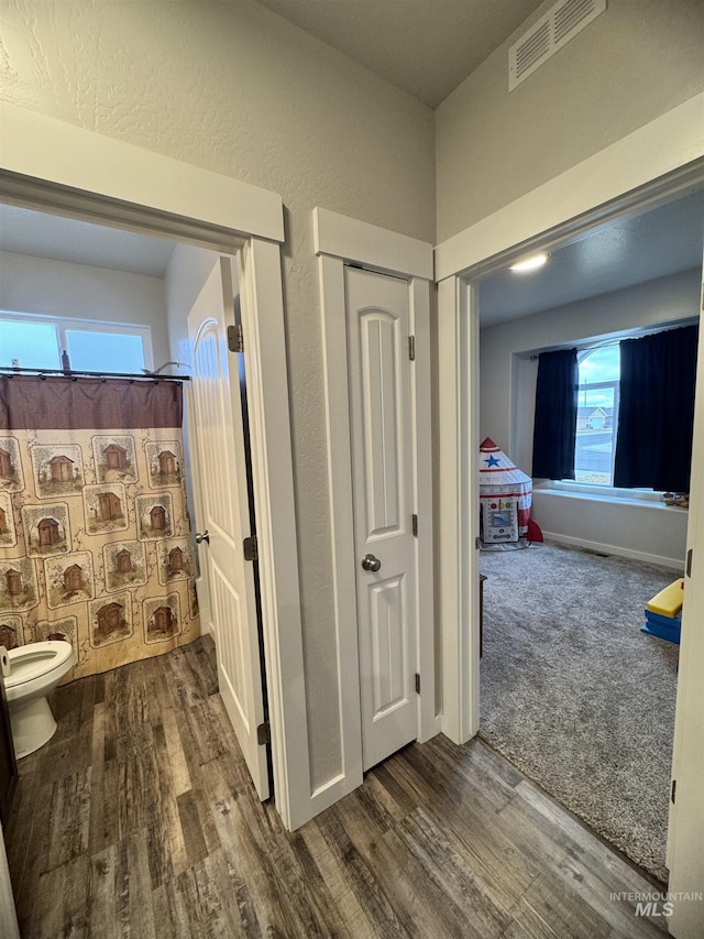 bathroom featuring a shower with shower curtain, hardwood / wood-style flooring, and toilet