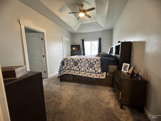 carpeted bedroom with a raised ceiling and ceiling fan