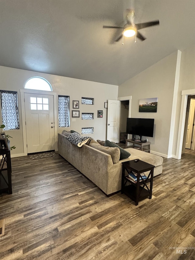 living room with ceiling fan, dark wood-type flooring, and vaulted ceiling