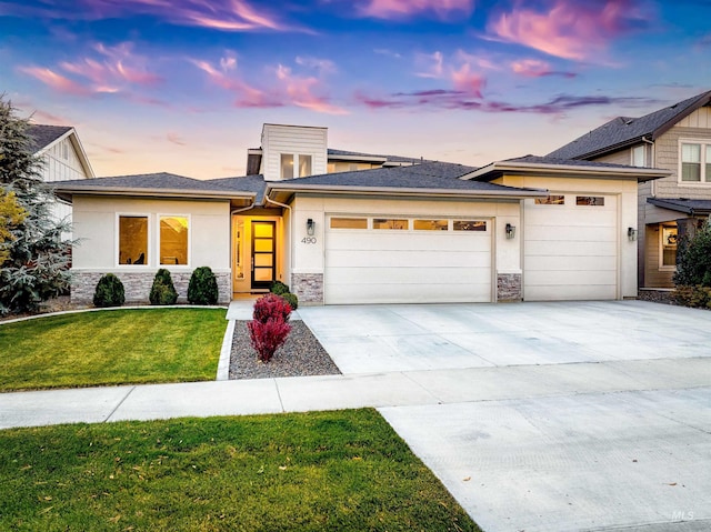 prairie-style home featuring a garage, stone siding, a front lawn, and concrete driveway