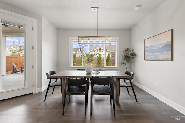 dining area with dark wood-style floors, a textured ceiling, baseboards, and a wealth of natural light