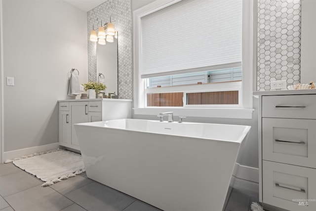 full bathroom featuring tile patterned flooring, a freestanding bath, vanity, and baseboards