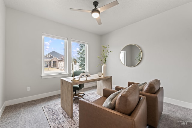 carpeted office space featuring ceiling fan and baseboards