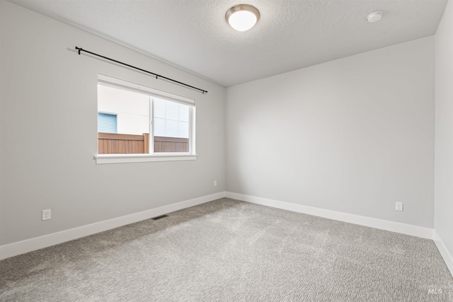 carpeted spare room featuring visible vents, a textured ceiling, and baseboards