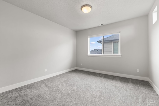 carpeted empty room with visible vents, baseboards, and a textured ceiling